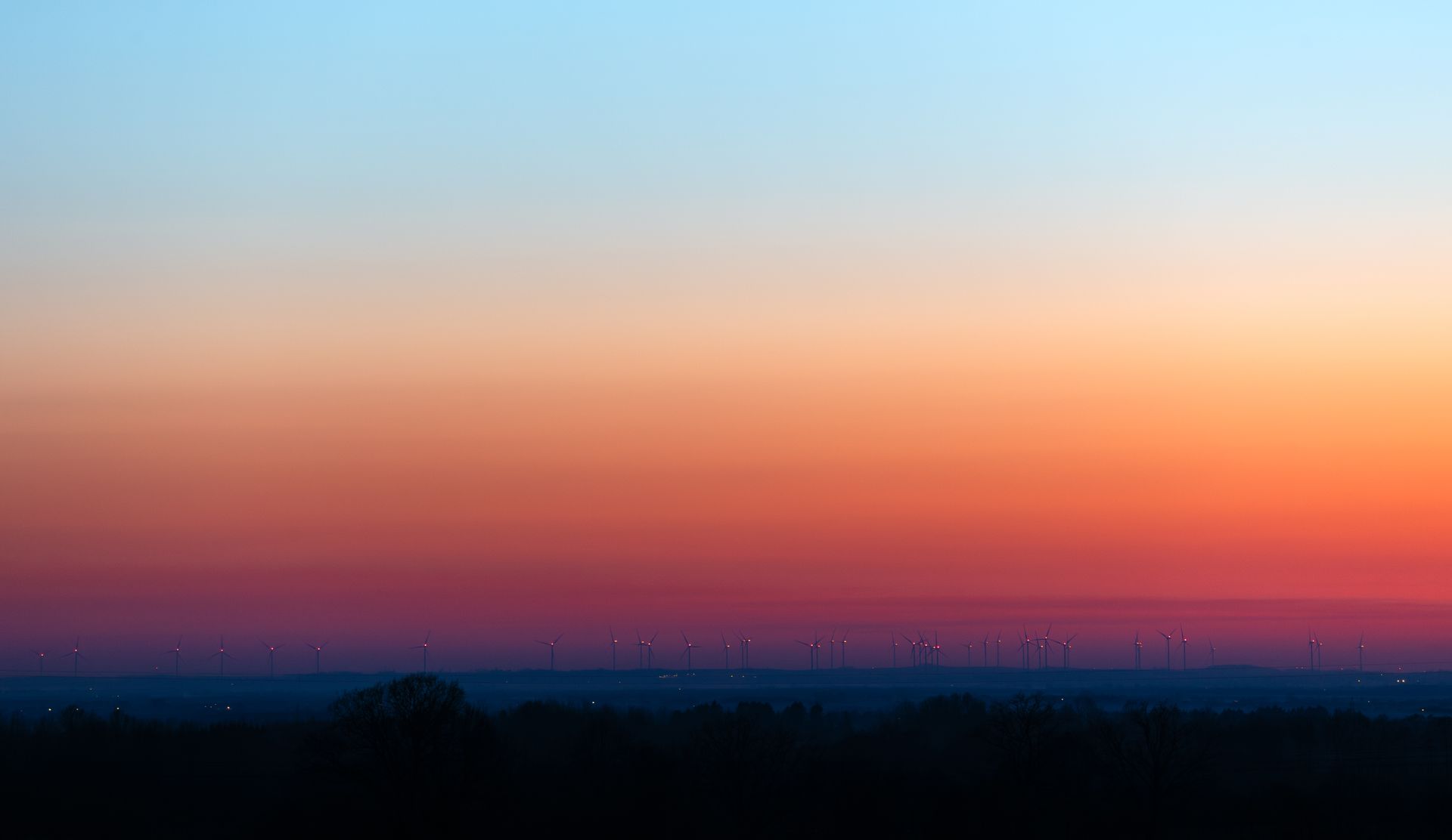 A stunning view of a wind farm silhouetted against a colorful sunset sky in Poland.