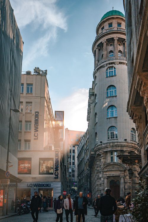 Free A bustling street with historic European architecture and people walking. Stock Photo