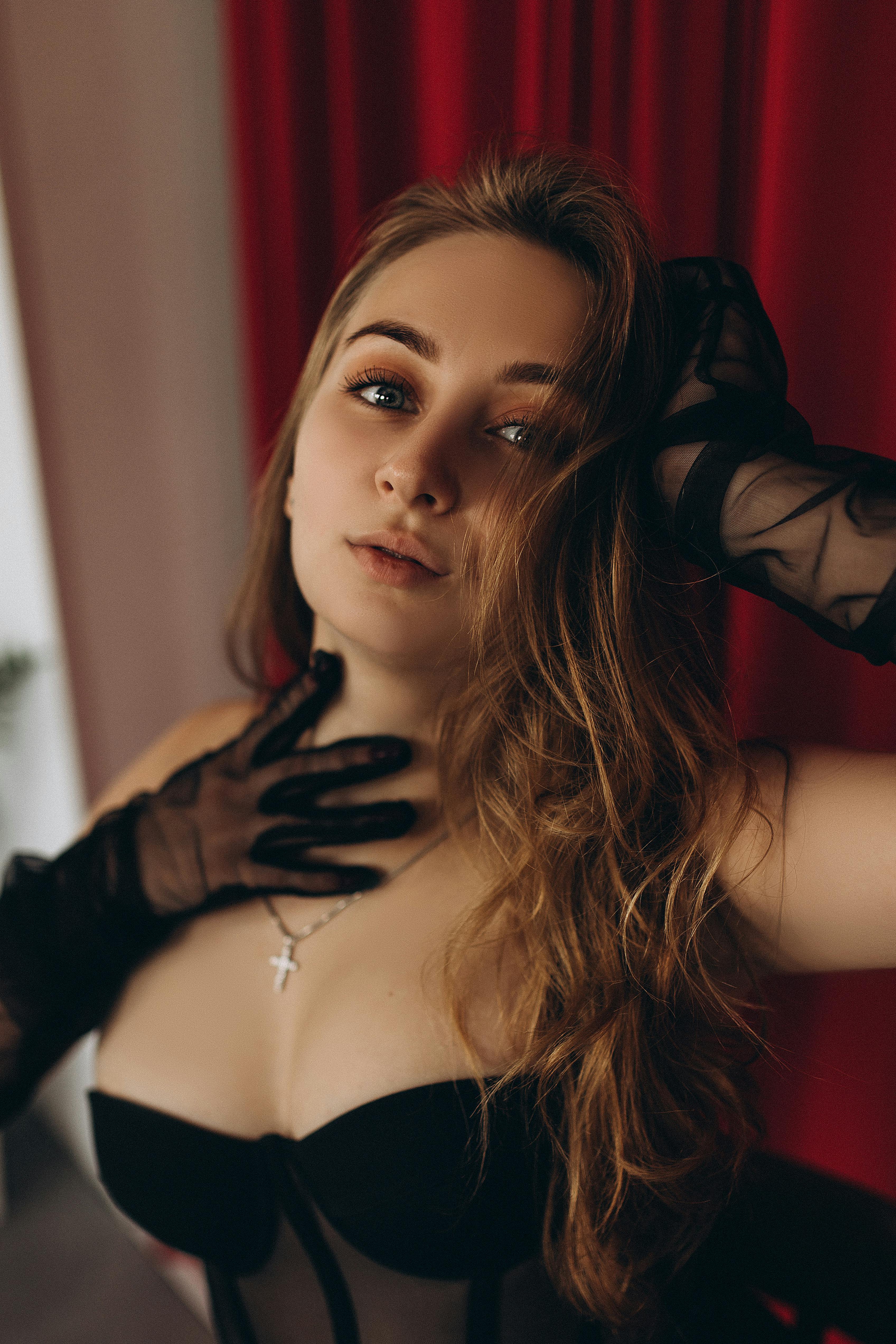Portrait of an elegant woman in black lingerie with mesh gloves and a cross necklace.