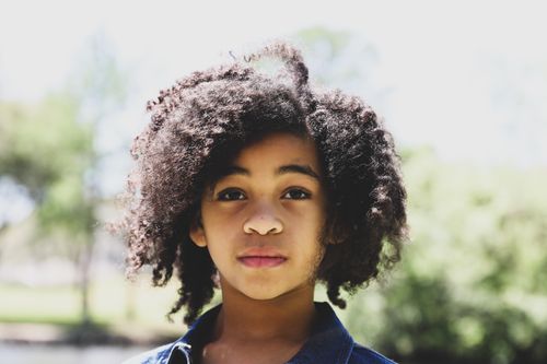 Free Beautiful outdoor portrait of a young girl in natural light with curly hair, evoking innocence and beauty. Stock Photo