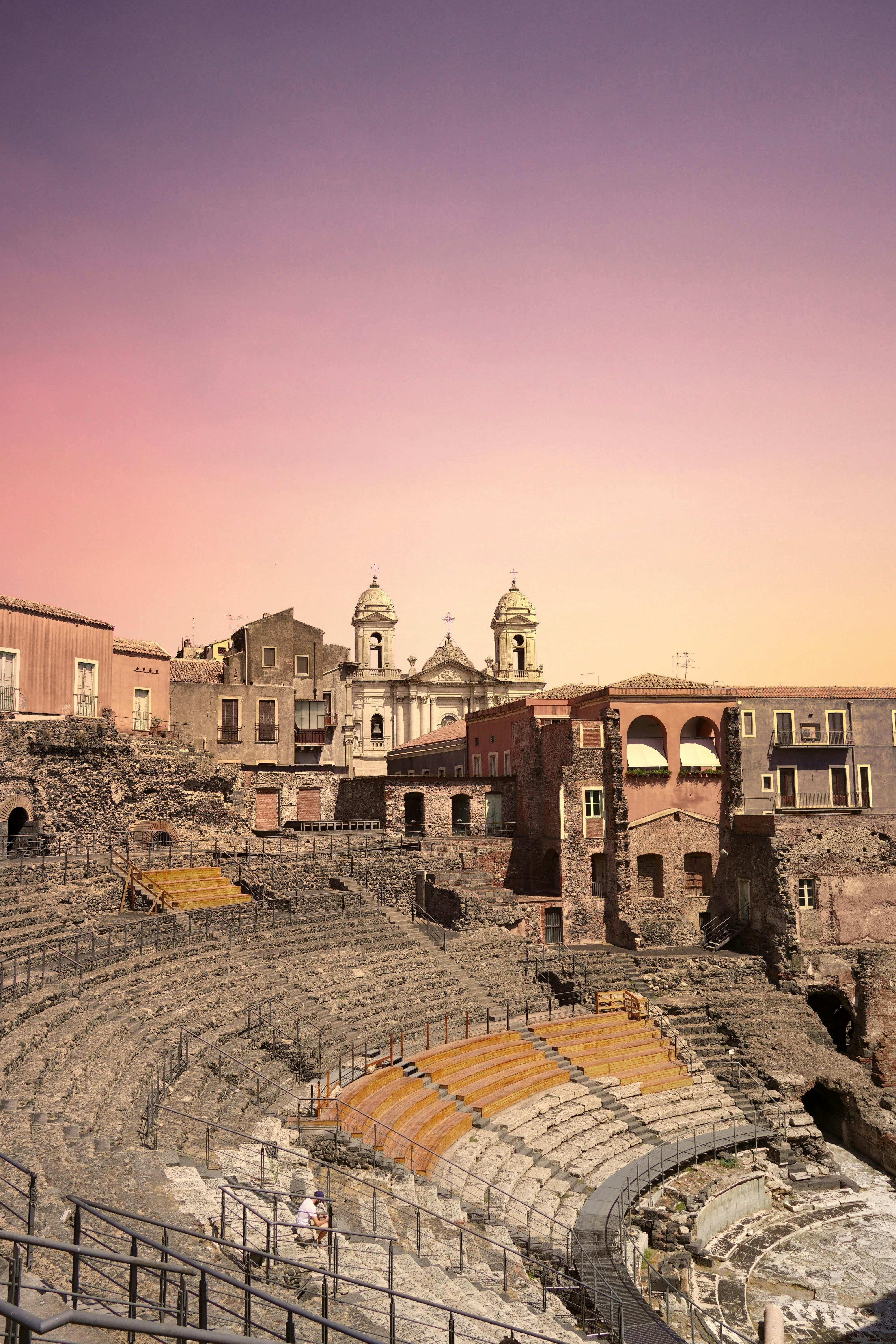 Kostenlos Faszinierender Blick auf das antike römische Amphitheater in Catania mit einem atemberaubenden Sonnenuntergangshimmel. Stock-Foto