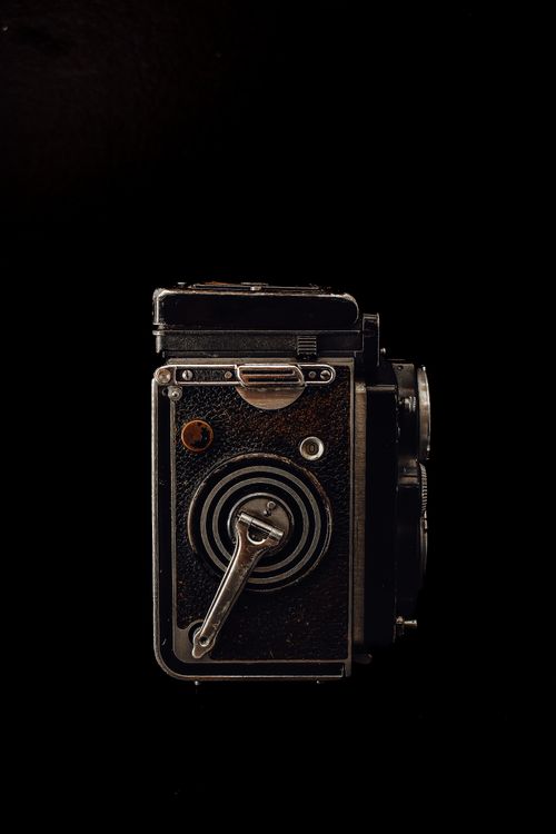 Free Antique box camera with a black backdrop, highlighting classic design. Stock Photo