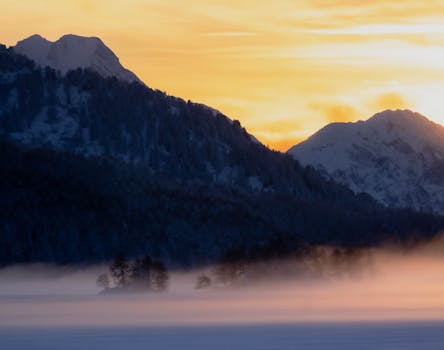 Stunning mountain view at sunrise with mist covering the landscape, creating a serene atmosphere.