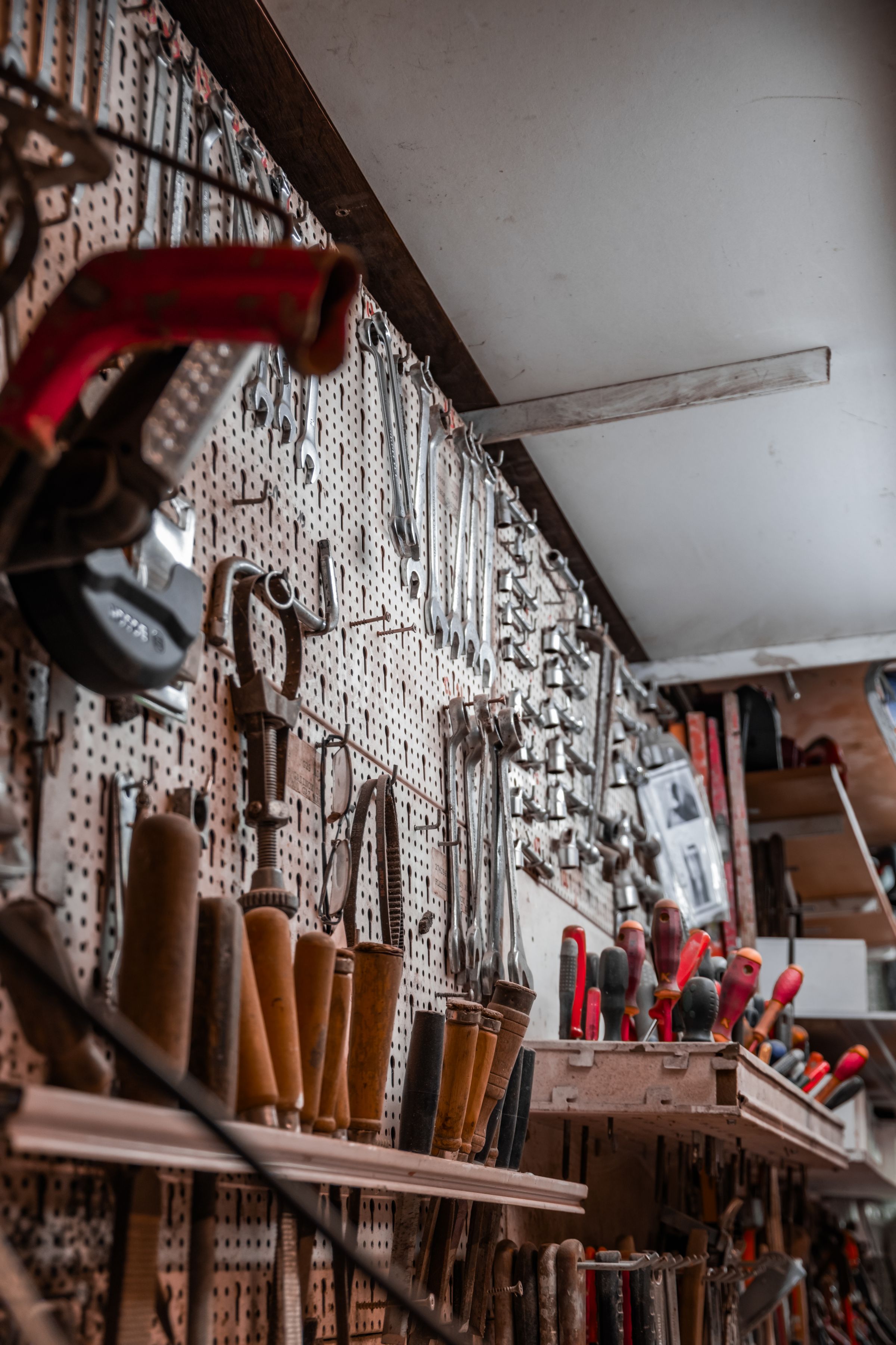 Organized workshop wall holding hammers, pliers, screwdrivers, wrenches, and repair tools