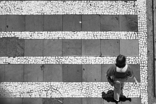Free Top view of a person crossing a patterned crosswalk in black and white. Urban life concept. Stock Photo