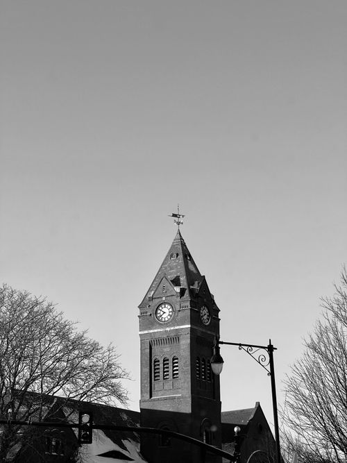 Free A timeless black and white image of a clock tower under a clear sky, capturing architectural elegance. Stock Photo