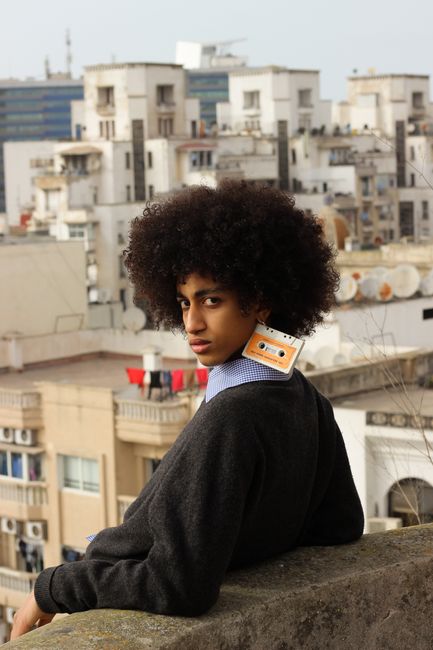 Stylish young man with cassette accessory overlooking Casablanca urban landscape.