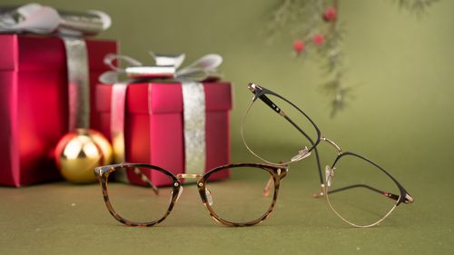 Free Elegant eyeglasses displayed with festive gift boxes, perfect holiday fashion accessory. Stock Photo