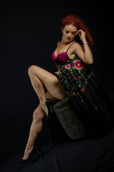 Captivating portrait of a woman in lingerie with an embroidered shawl against a dark background.