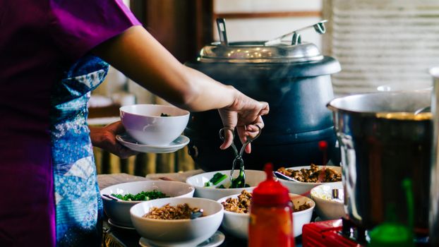 A person serves themselves at a traditional Indonesian buffet in West Java, Indonesia.