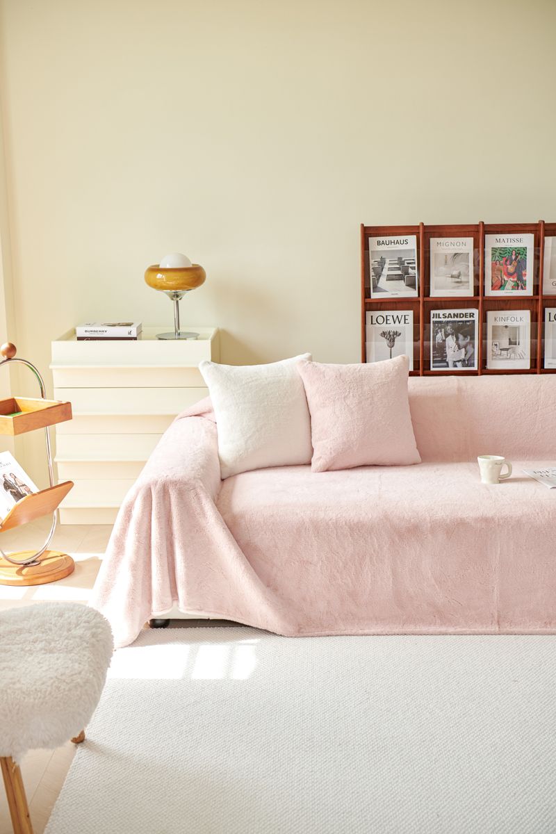 A cozy living room with a pink sofa cover draped neatly over a couch
