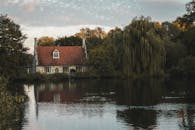 郁郁葱葱的树木环绕着风景如画的湖边小屋，倒映在平静的水面上