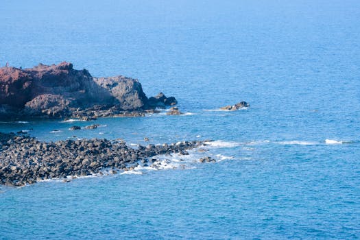 A scenic view of a rocky coastline meeting the clear blue ocean waters, ideal for travel and nature themes.