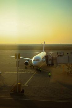 A commercial airplane parked at Erbil Airport during a warm sunset, preparing for boarding.