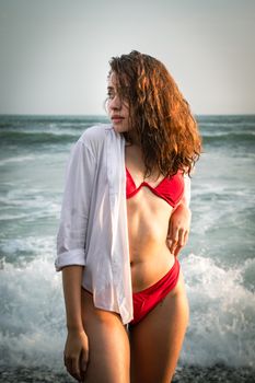 Young woman in a red bikini enjoying the beach in Lima, Peru with ocean waves in the background.