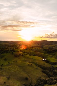 A breathtaking aerial view of a golden sunset over lush, rolling hills.
