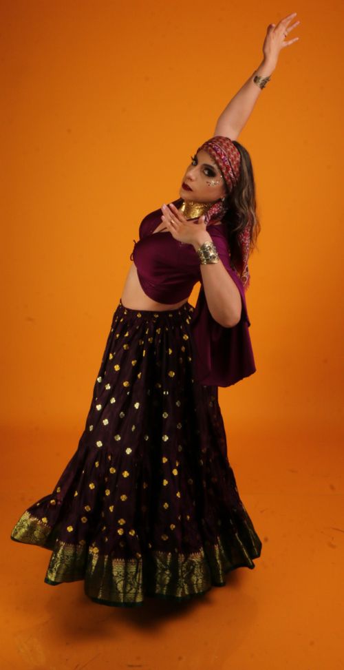 Free A dancer in traditional ethnic clothing posing gracefully against an orange backdrop. Stock Photo