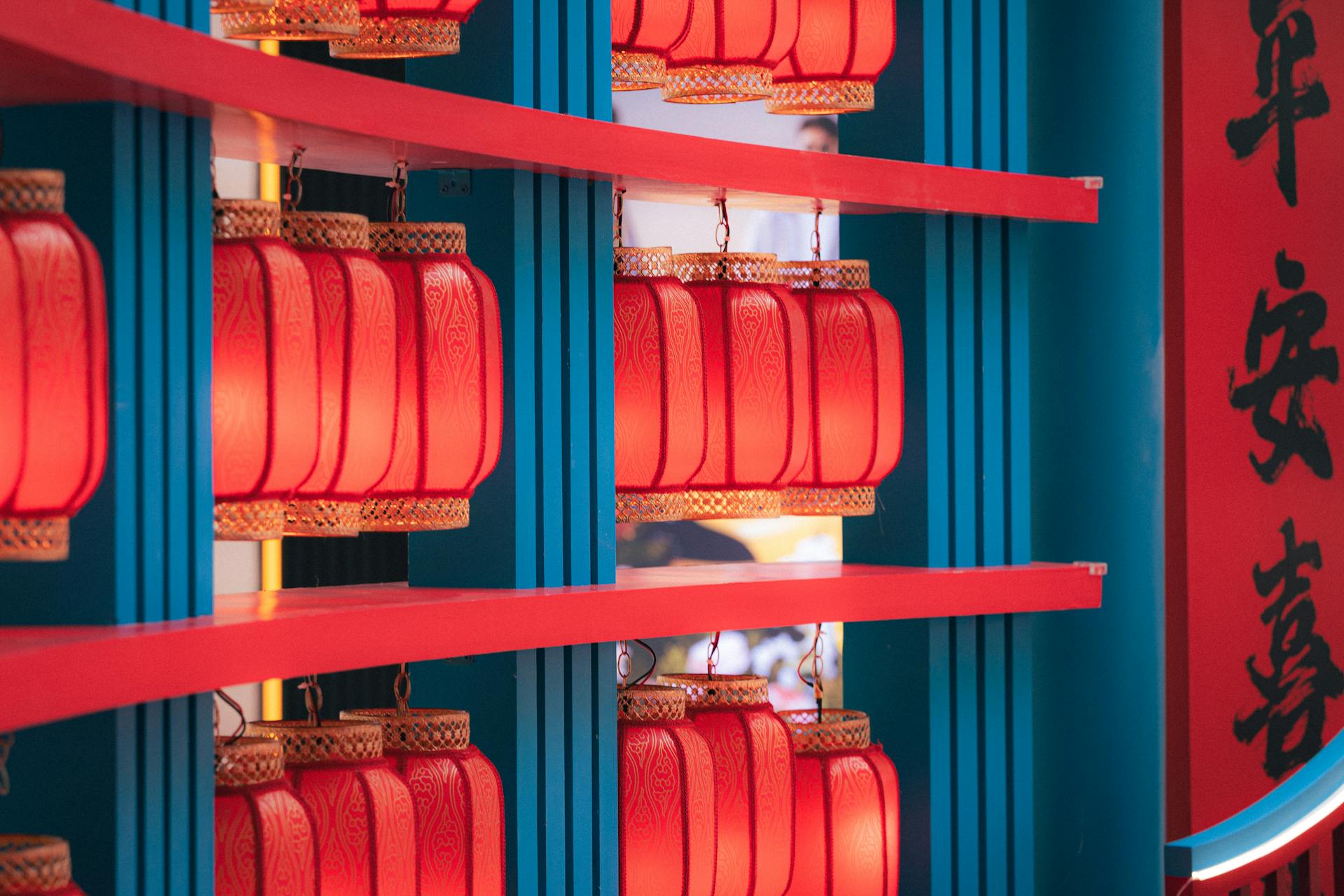 Vibrant red lanterns hang gracefully on blue supports with intricate patterns, symbolizing good fortune and joy during the Chinese New Year celebrations