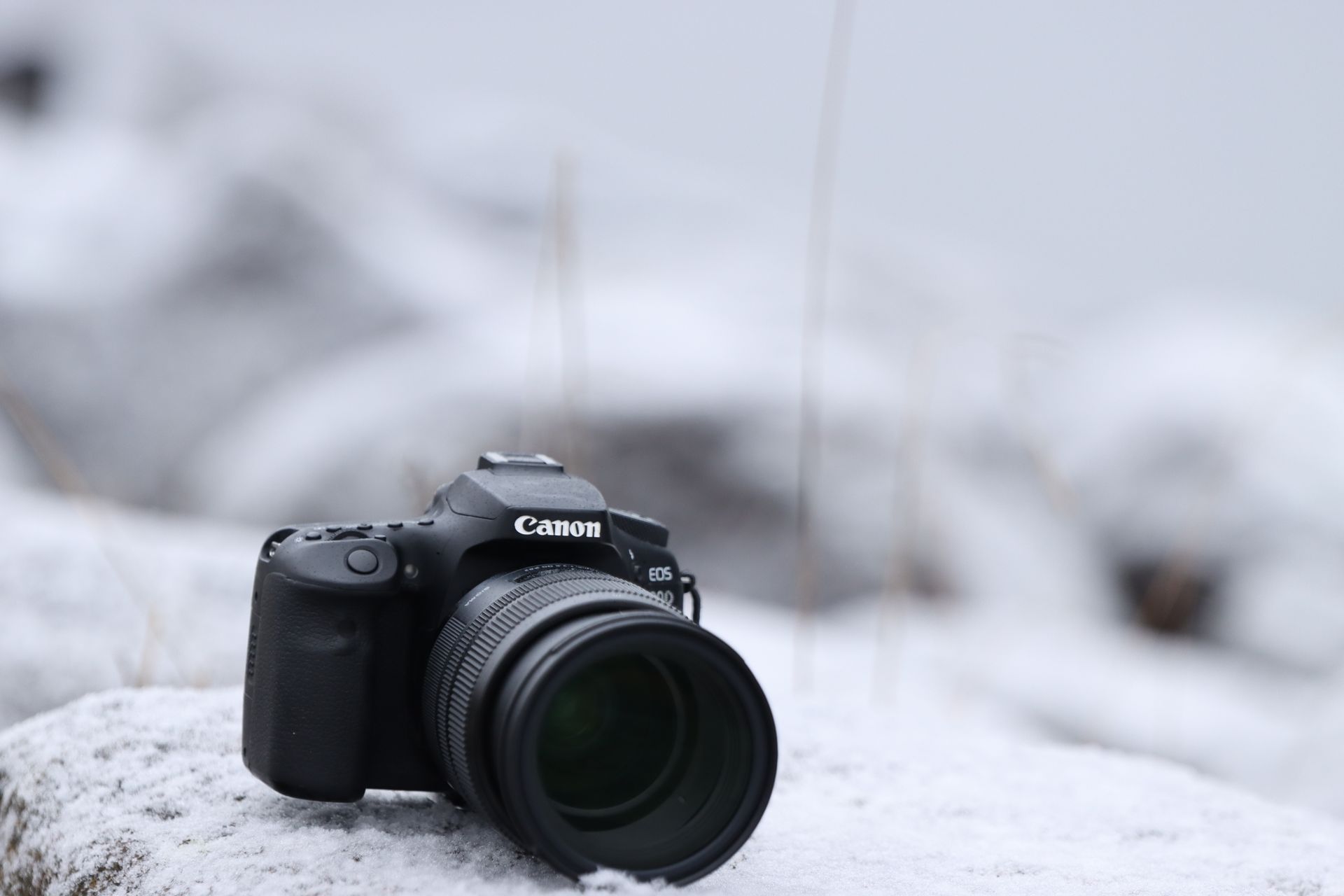 A Canon EOS camera rests on a snow-covered surface in Jönköping, Sweden, during winter.