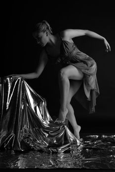 Artistic black and white portrait of a female dancer in an elegant pose with metallic fabric.
