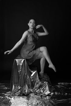 Stunning black and white photo of a contemporary dancer in artistic pose with metallic backdrop.