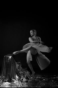 Elegant ballerina captured mid-performance against a dark, dramatic backdrop.