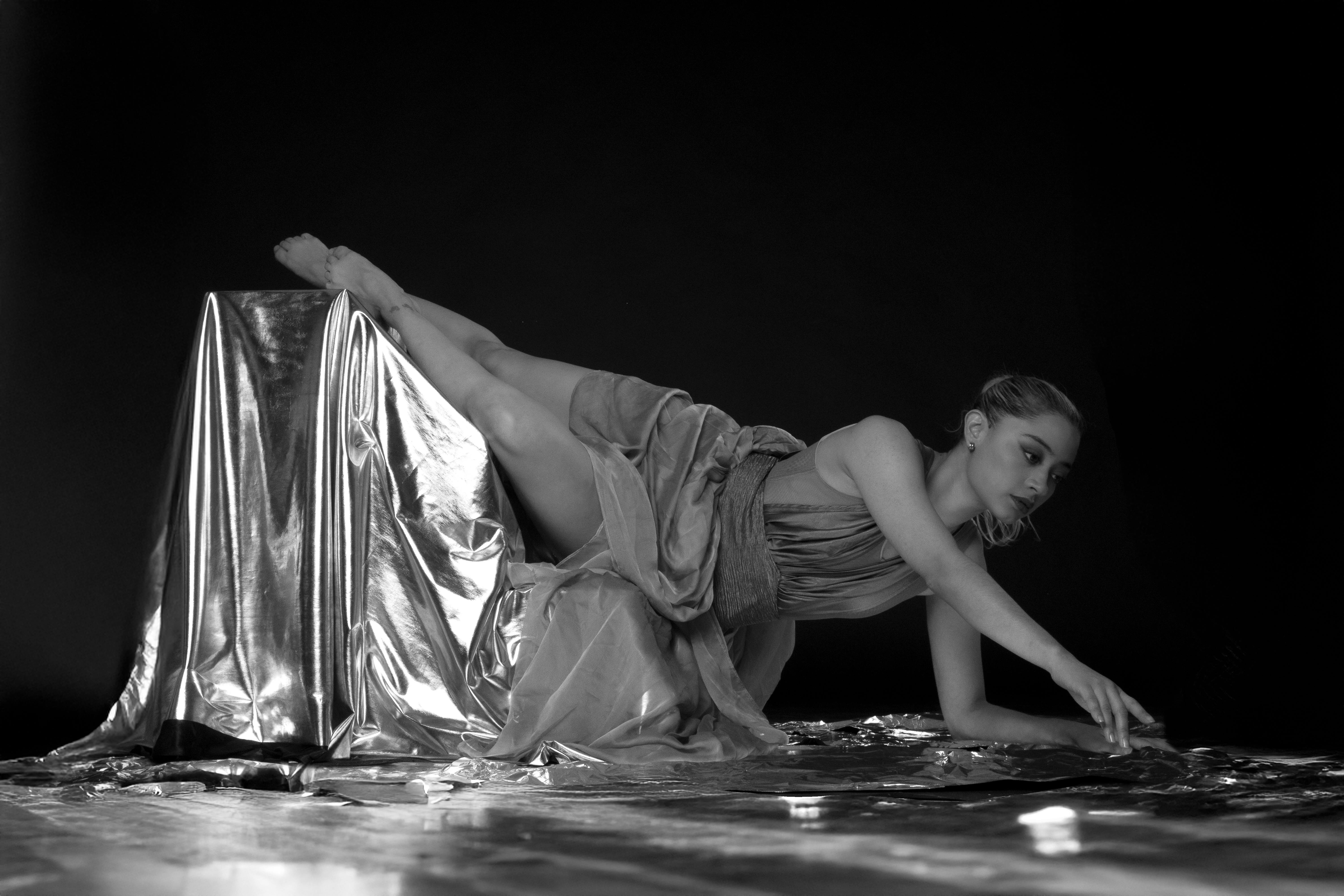 Kostenlos Künstlerisches Schwarzweißbild einer Ballerina in einer eleganten Tanzpose, gehüllt in metallischen Stoff. Stock-Foto