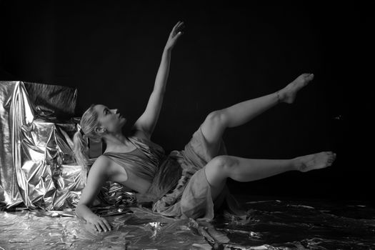A contemporary dancer in a graceful pose against a metallic backdrop in black and white.