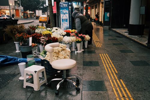 Free A vibrant street scene showcasing a colorful flower market with various blossoms on a city sidewalk. Stock Photo