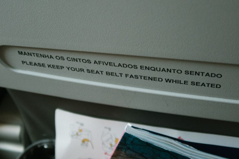 Close-up of an airplane seatback pocket with a seat belt safety message in English and Portuguese.