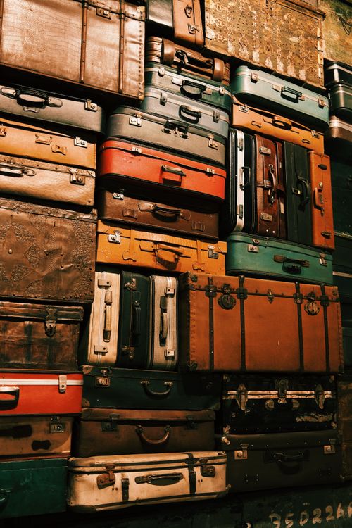 Free A wall adorned with a variety of stacked vintage suitcases in rich tones. Stock Photo