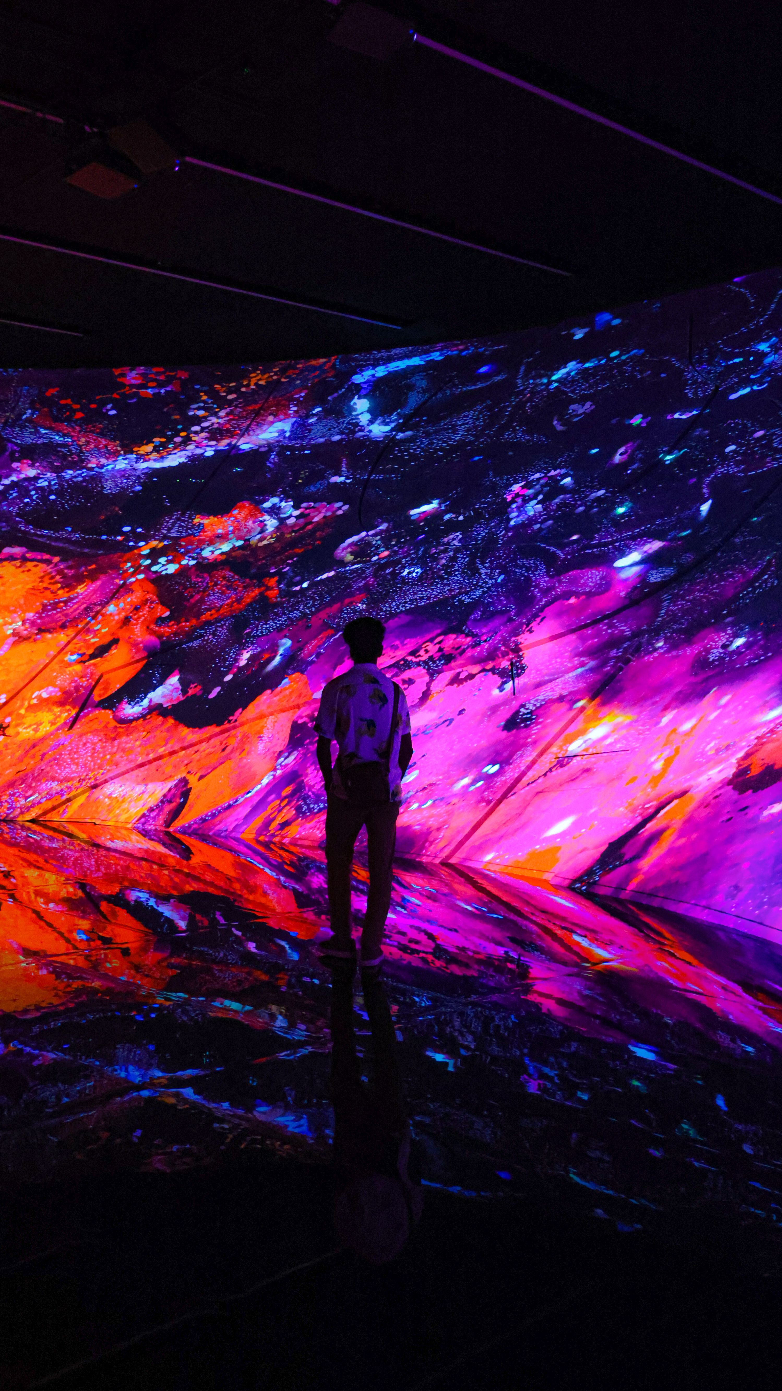 Child interacting with glowing digital fish projections at teamLab FutureWorld exhibition in ArtScience Museum, Marina Bay Singapore