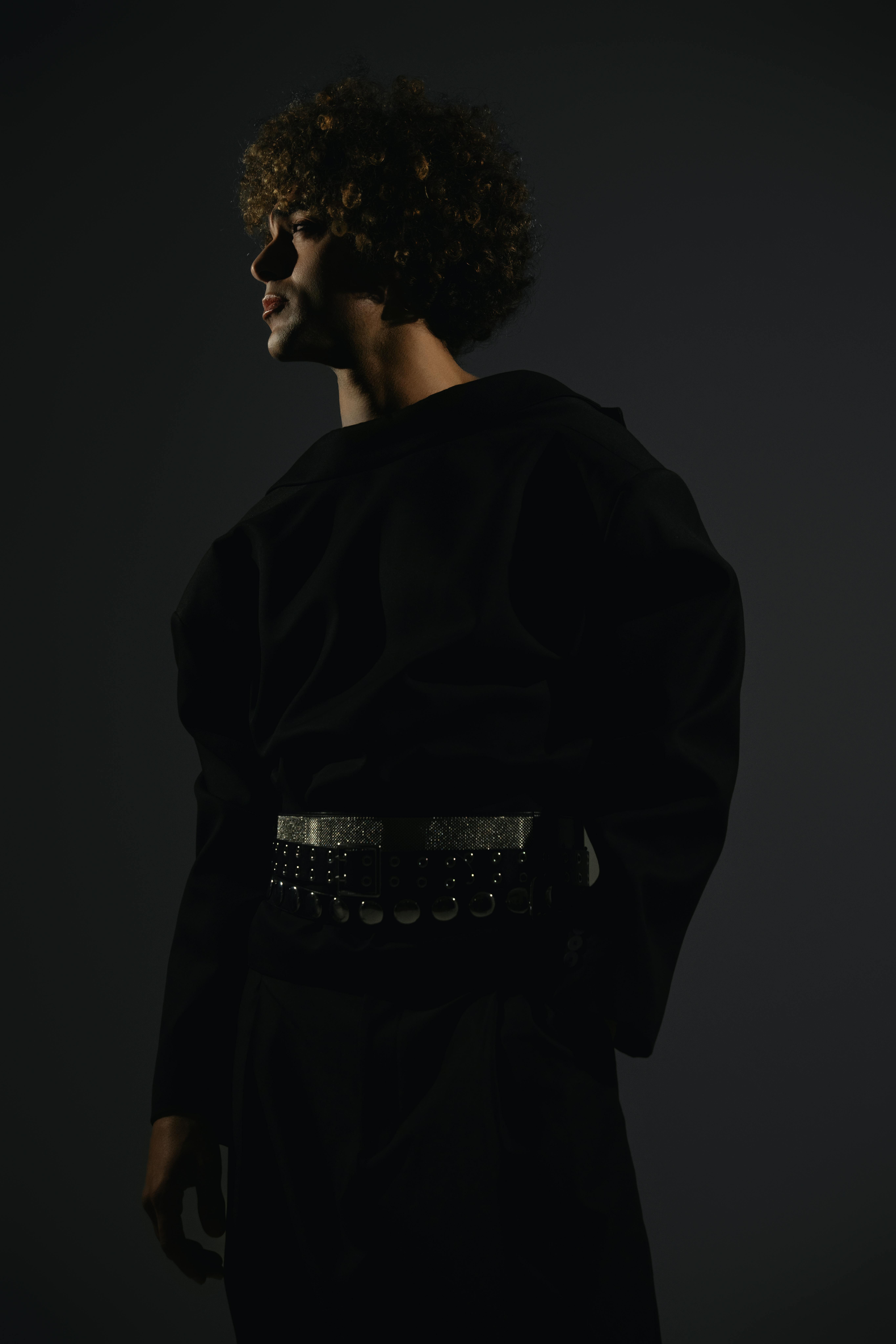 Stylish male model in a dark, dramatic fashion portrait with moody lighting.