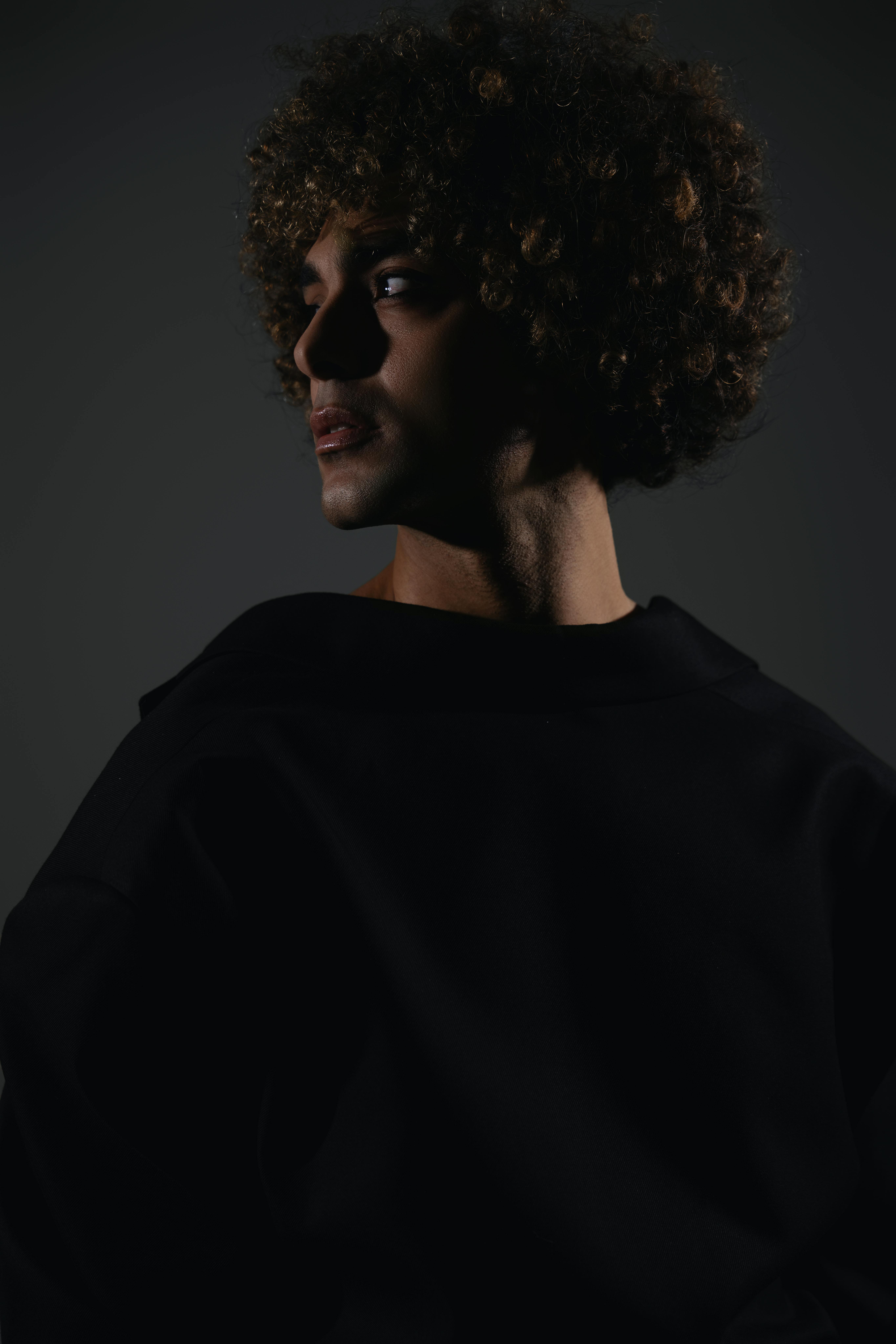 Moody and dramatic fashion portrait of male model in dark tones, shot in London studio.