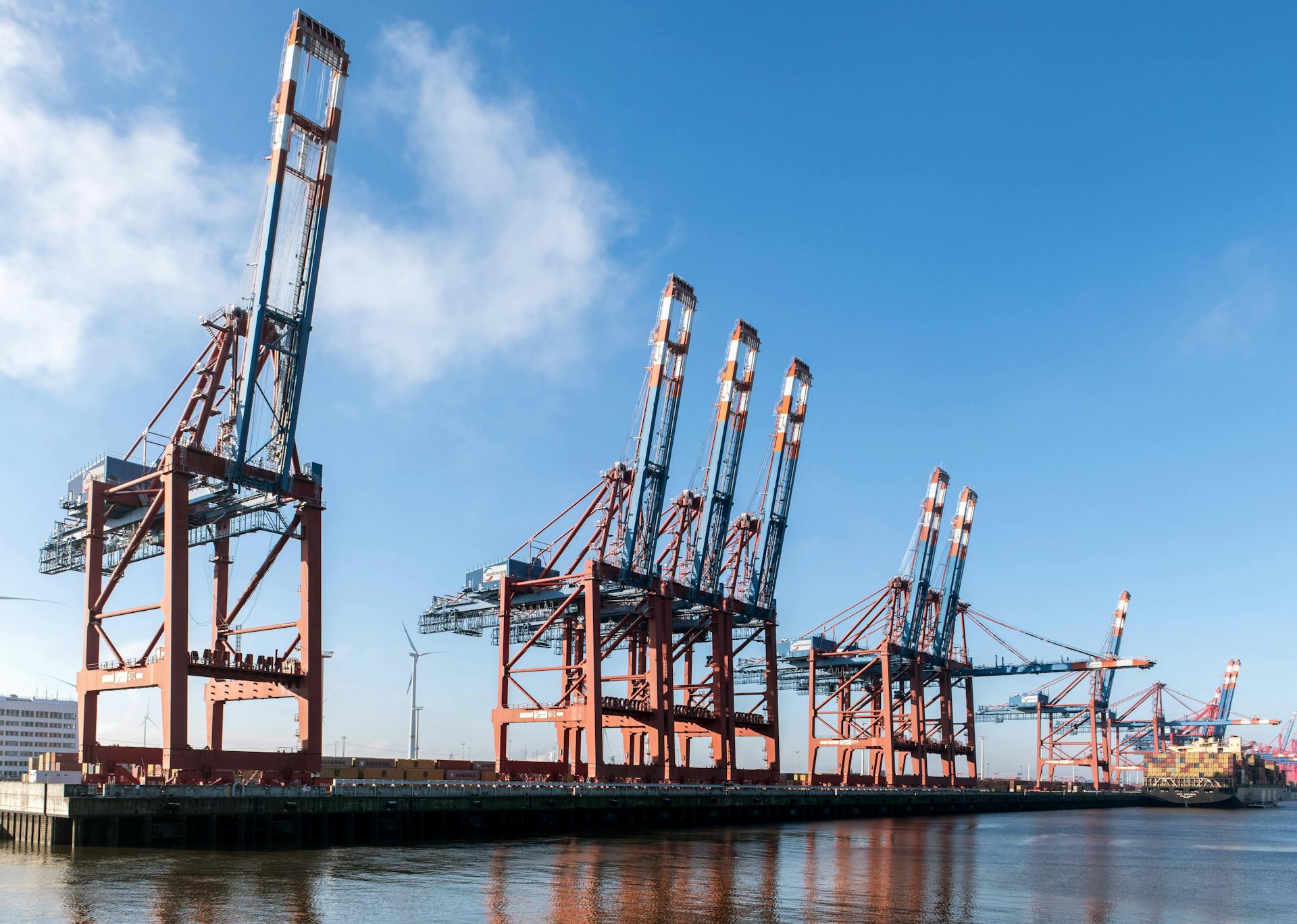 Massive container cranes at Hamburg port with a cargo ship docked, showcasing global trade hub.