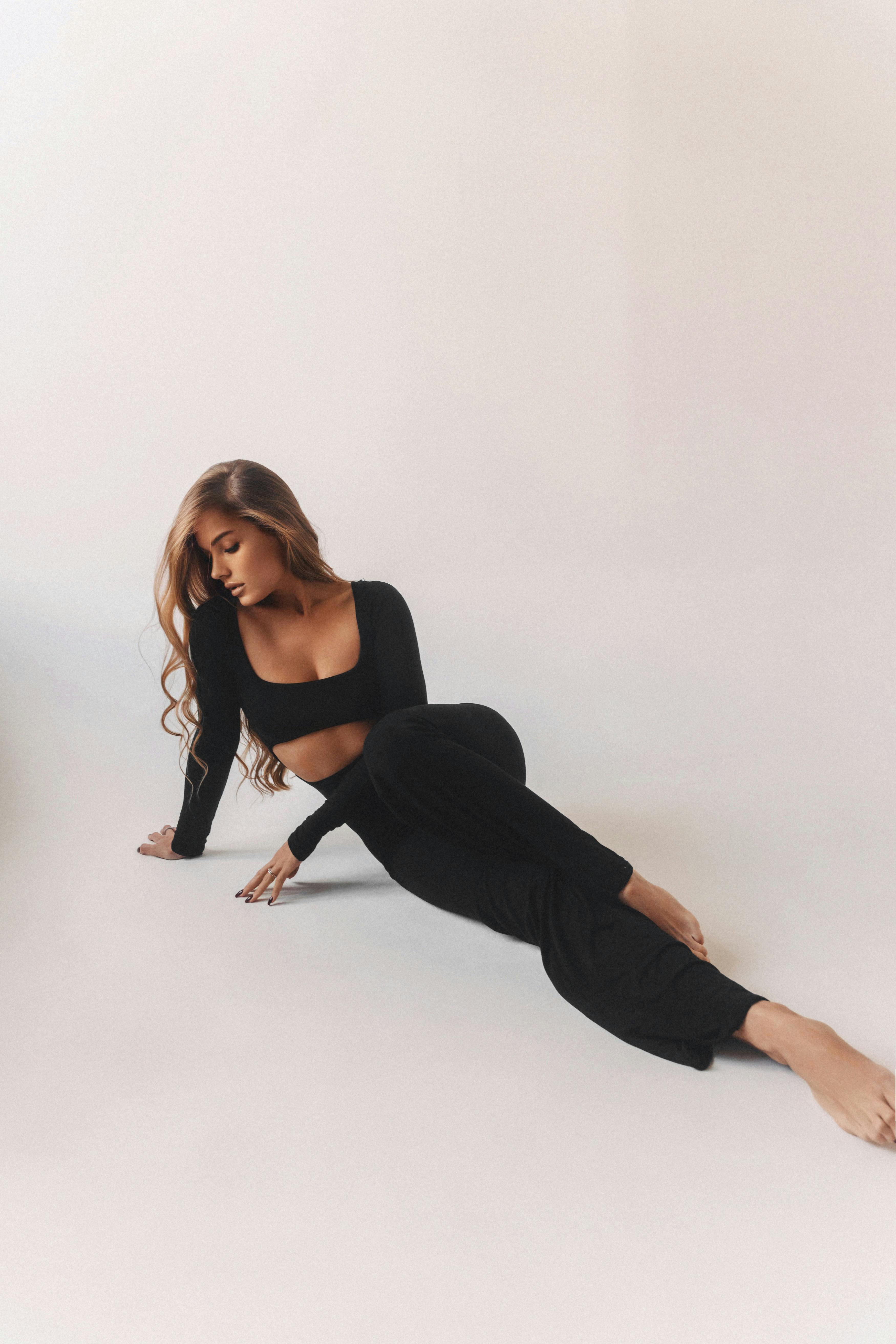 Woman in stylish black attire posing gracefully against a white backdrop.
