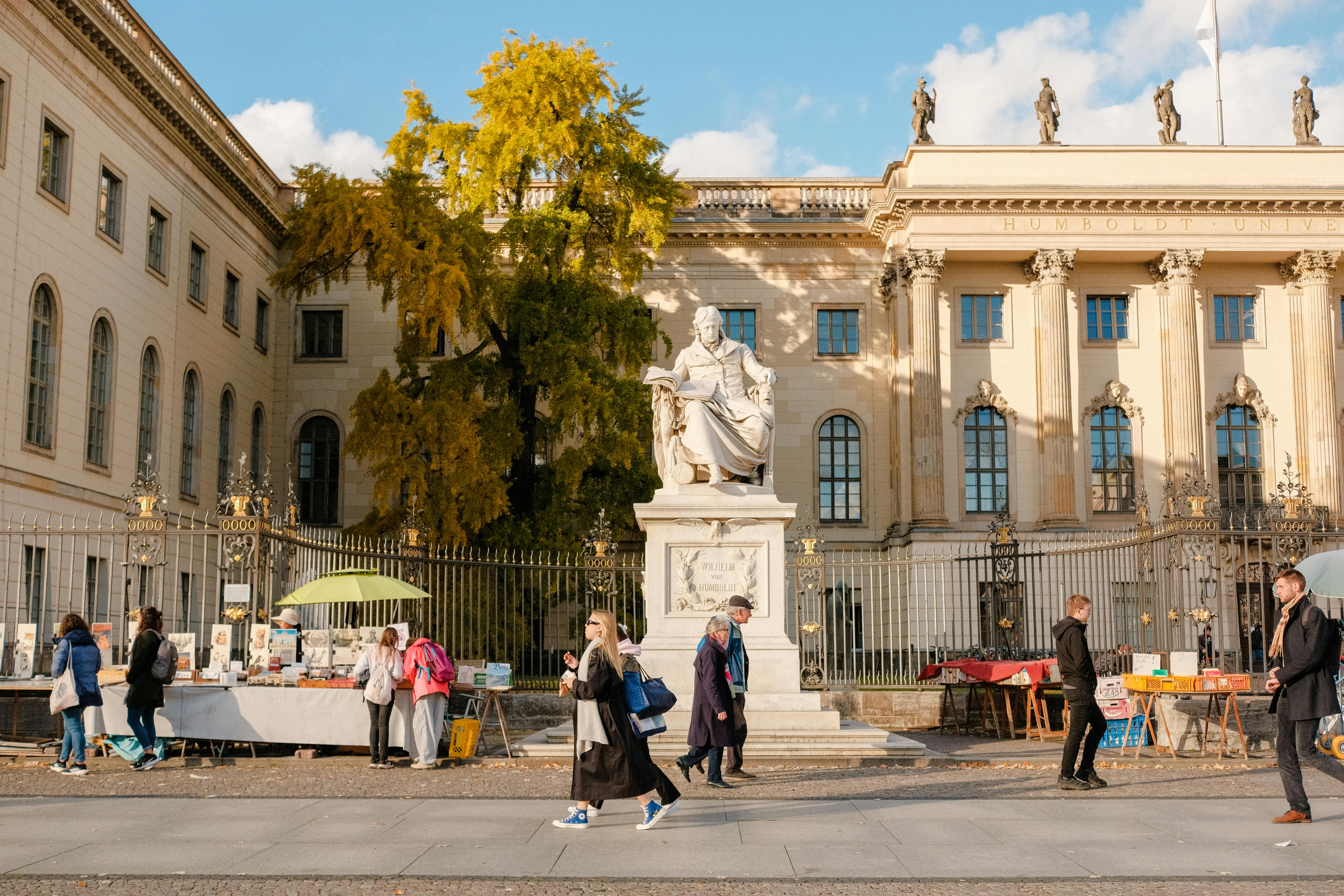 Street scene at Humboldt University with market stalls and pedestrians in Berlin.