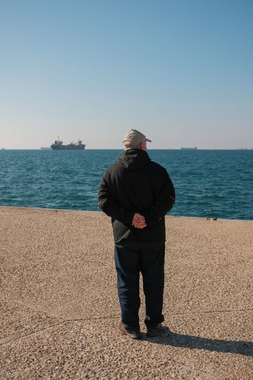 Free Man observing ships at sea in Thessaloniki, Greece on a clear day. Stock Photo