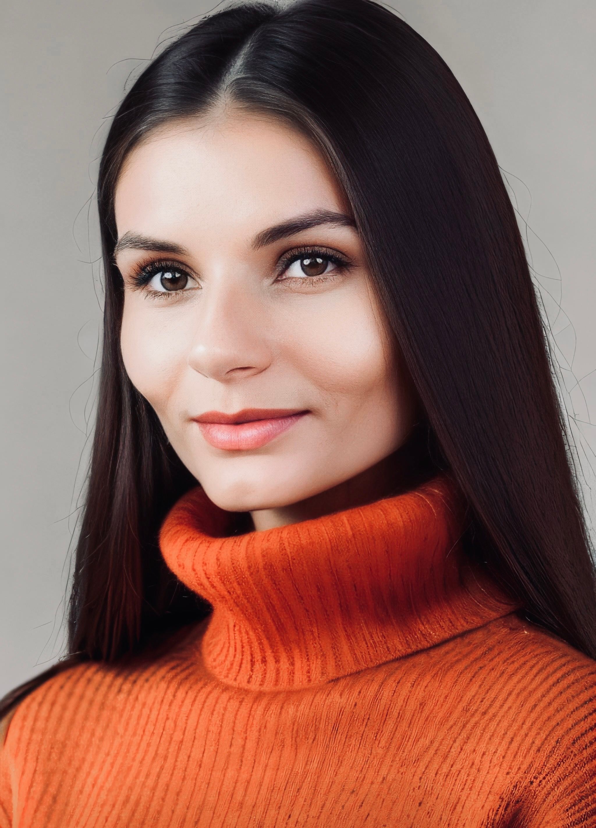 Close-up portrait of a woman wearing an orange turtleneck sweater, exuding a calm expression.