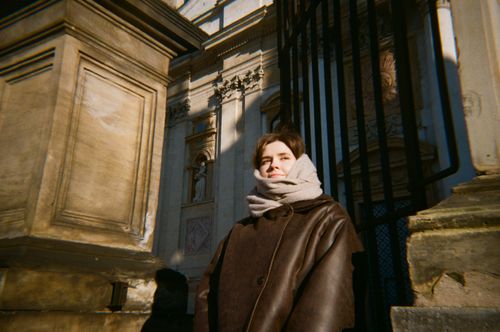 Free A person wearing a scarf and coat stands by a historic structure in Krakow, Poland. Stock Photo