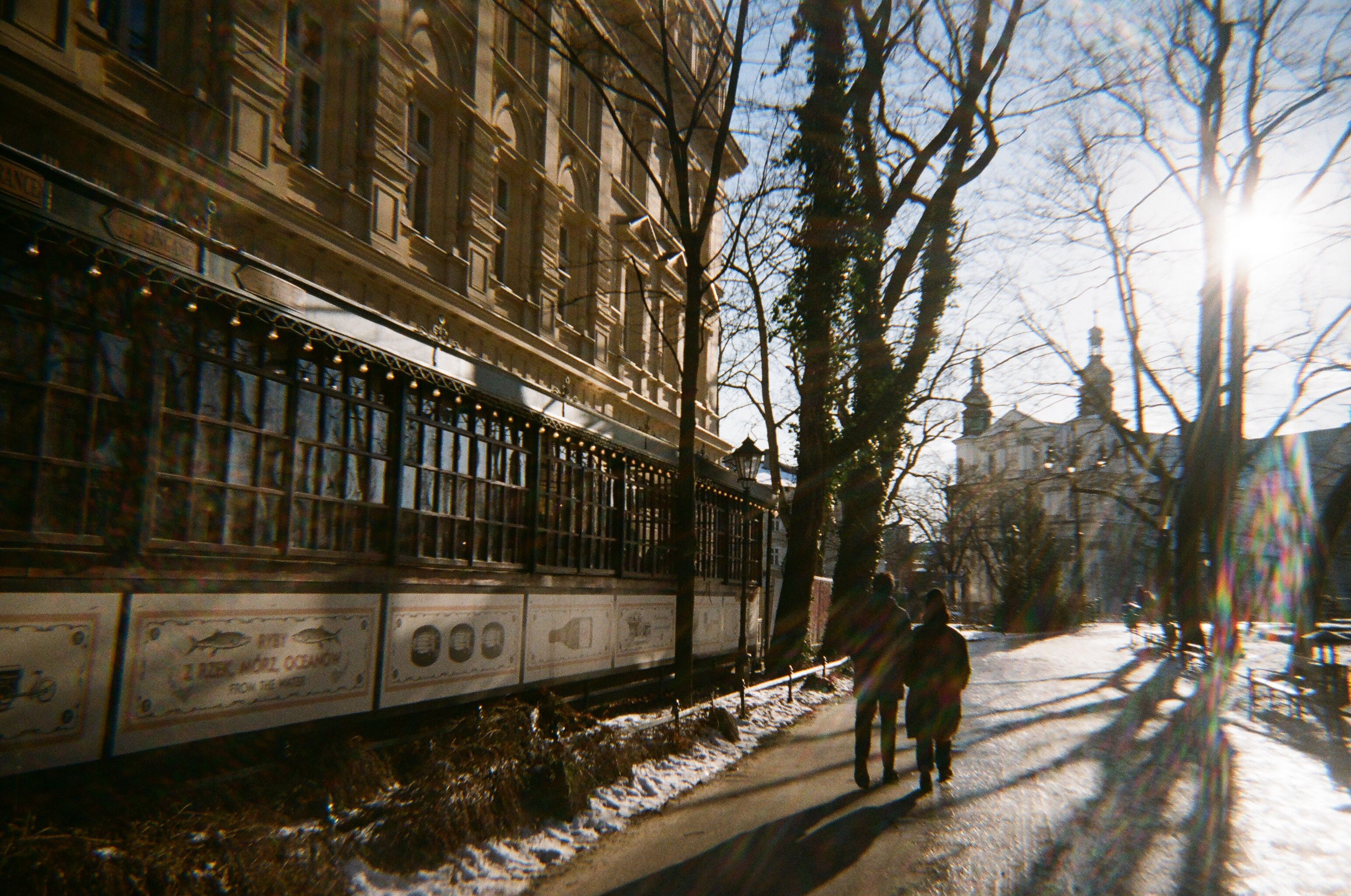 People bundled in warm winter coats, hats, and gloves walking on a snowy street in Krakow, Poland.