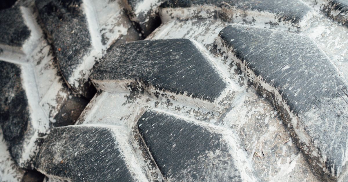 Detailed view of a worn tractor tire showing its deep tread pattern and grooves.