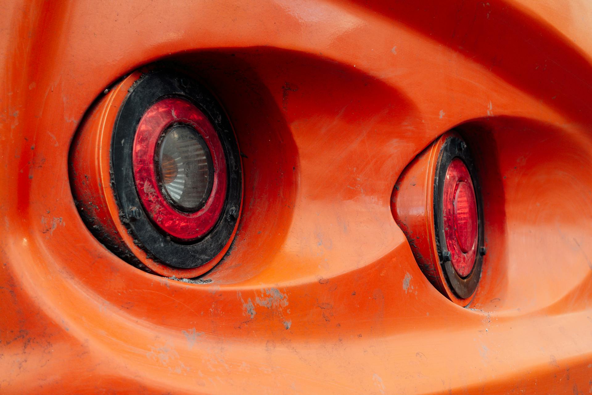 Detailed close-up of rusty orange vehicle taillights showing wear and dirt on the exterior surface.