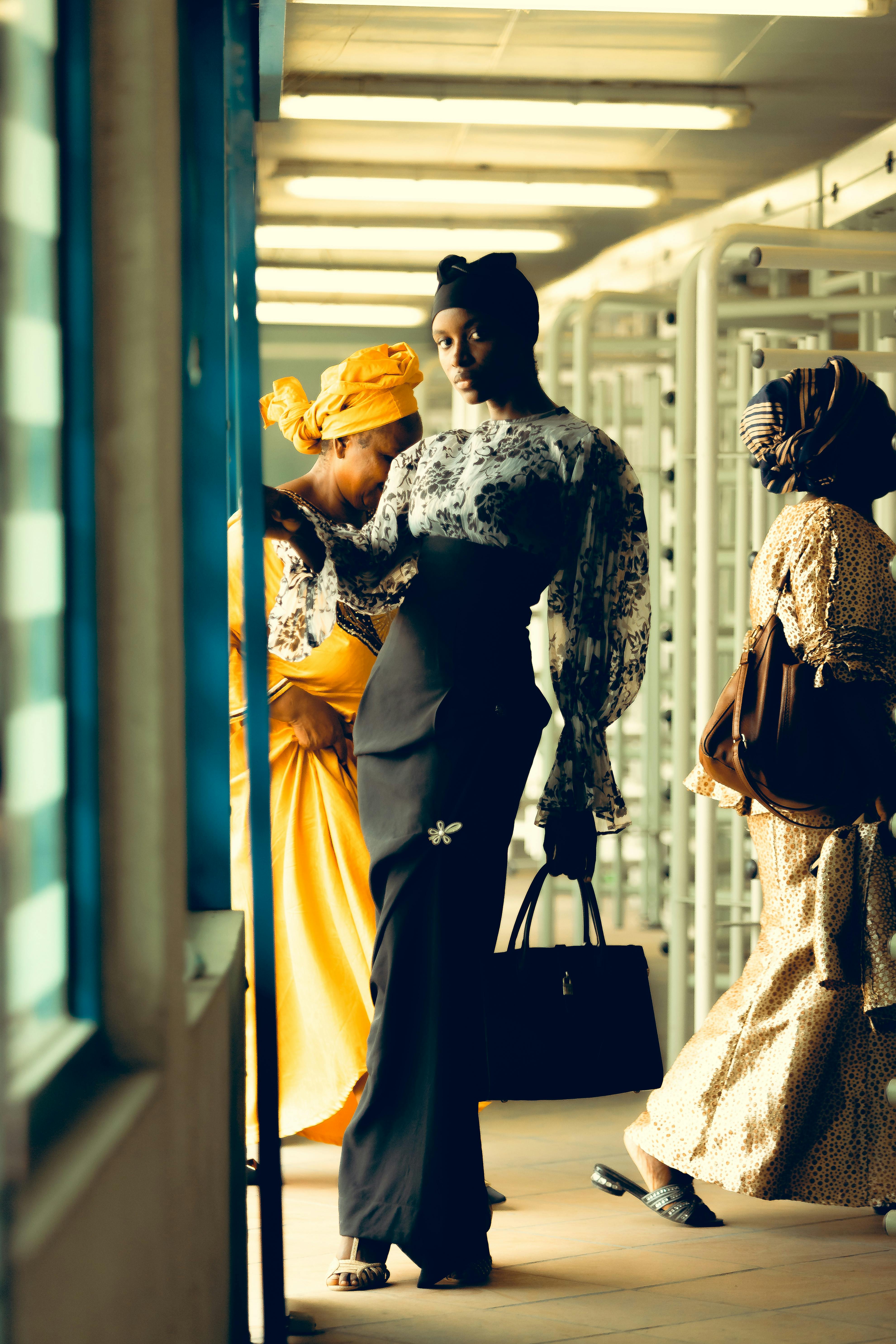 Three women in fashionable attire walking in an urban environment.
