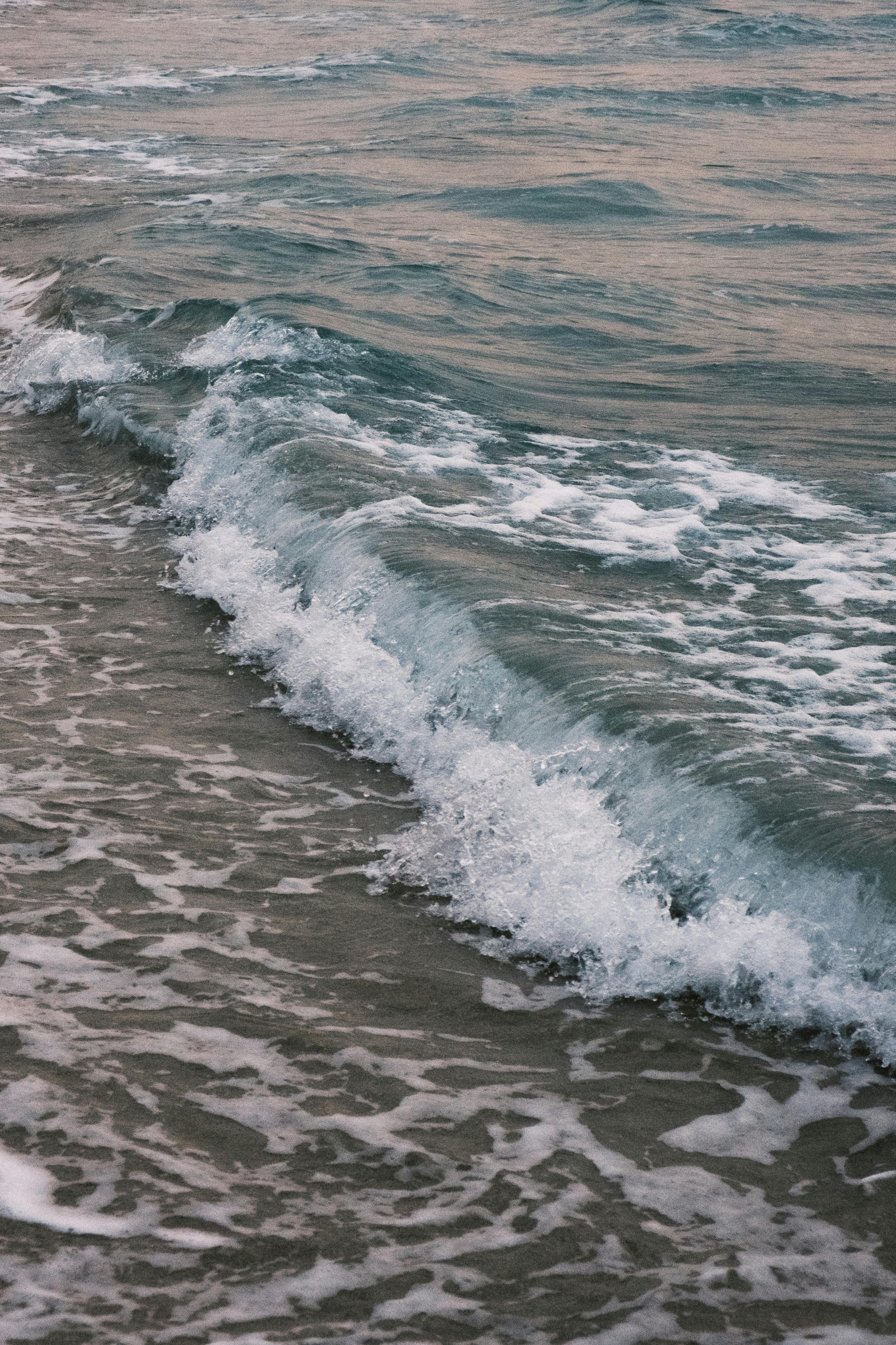 Gentle waves rolling onto the shore, captured in soft evening light.