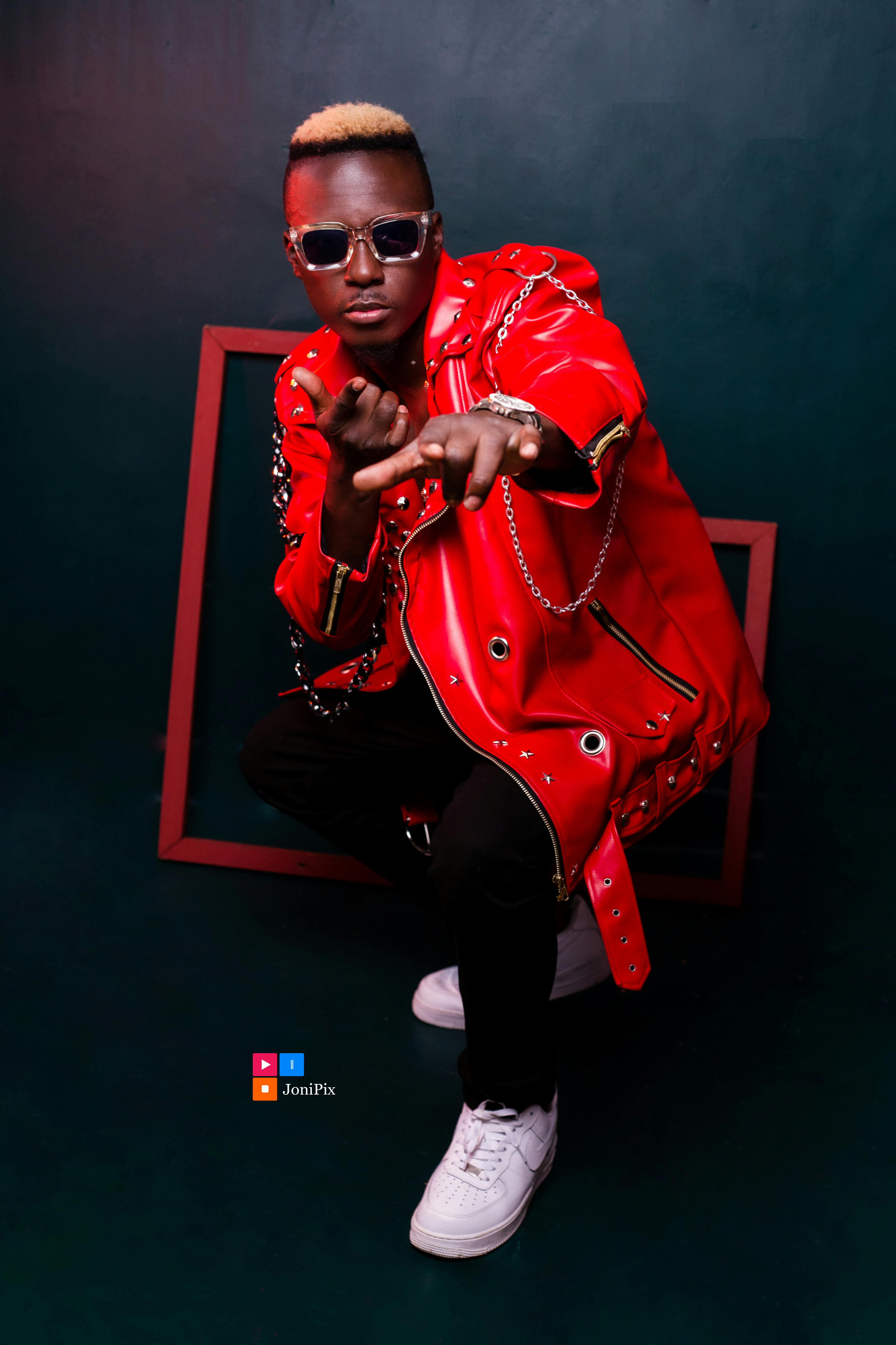 Man in vibrant red jacket and sunglasses poses confidently against a dark backdrop.