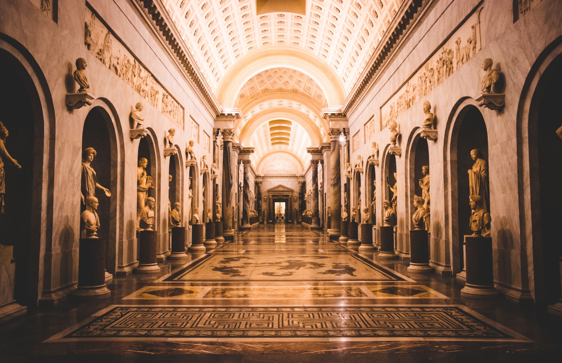 A stunning view of a hallway adorned with classical sculptures in the Vatican Museums.