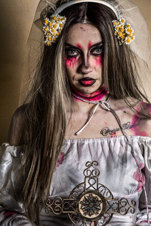 Free A woman in a haunting bridal costume holding an ornate cross. Stock Photo