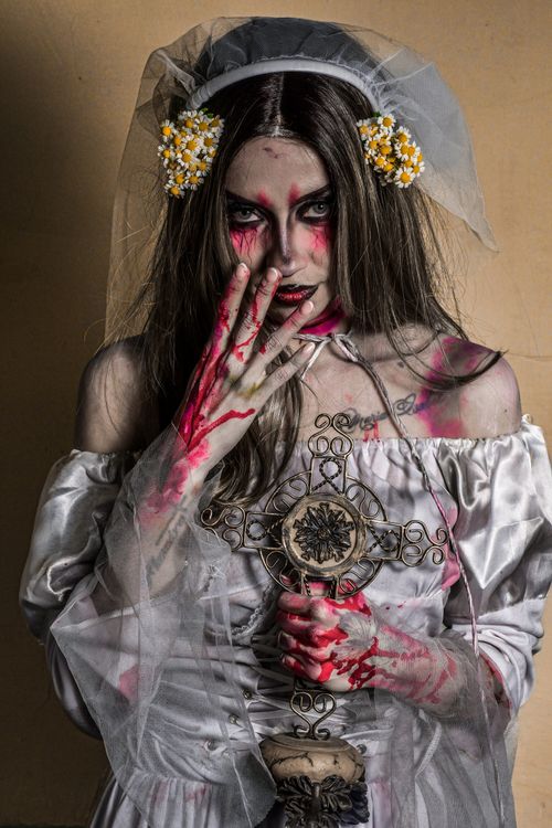 Free Creepy zombie bride holding a cross, perfect for Halloween themes. Stock Photo