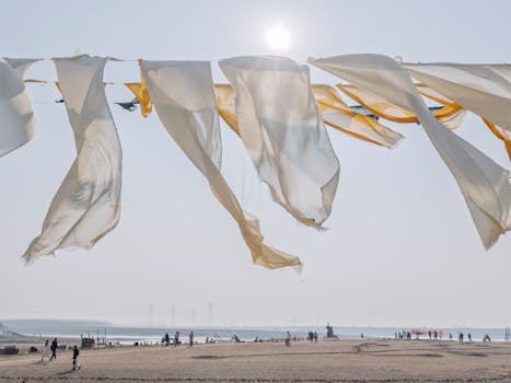 Flowing fabric on a sunny beach day, people enjoying outdoor activities.